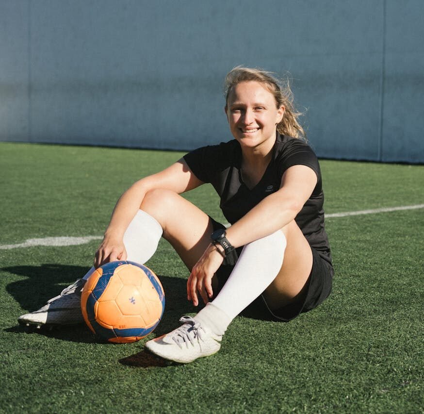 Soccer Player Sitting On A Green Field